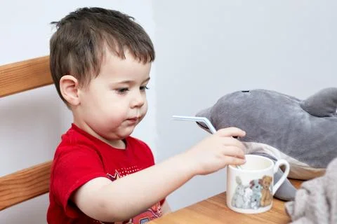Expressive boy drinking orange juice through a plastic straw Stock Photos