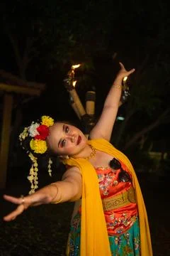 Expressive Indonesian dancer performing with raised arms and colorful costume Stock Photos
