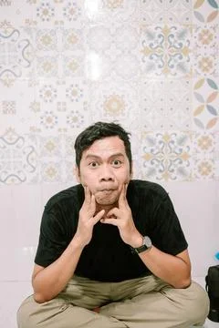Expressive man making funny faces with decorative tile background Stockfoto's