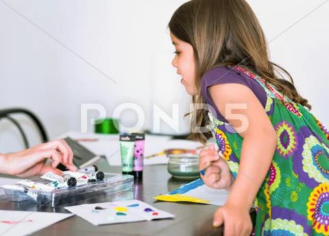 Expressive portrait of a pretty young girl doing paint with her mom Stock Photos