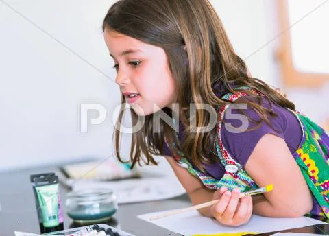 Expressive portrait of a pretty young girl doing paint with her mom Stock Photos