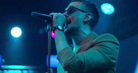 Expressive singer in glasses singing into microphone. Live music concert in Stock Footage 194972529