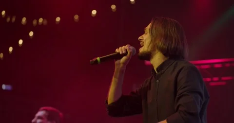 Expressive singer singing into microphone. Live music concert in front of bright Stock Footage 154894208