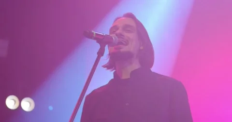 Expressive singer singing into microphone. Live music concert in front of bright Stock Footage 154913532