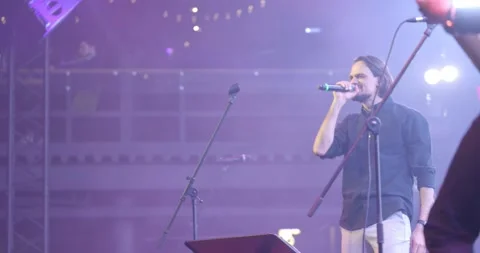 Expressive singer singing into microphone. Live music concert in front of bright Stock Footage 154913871