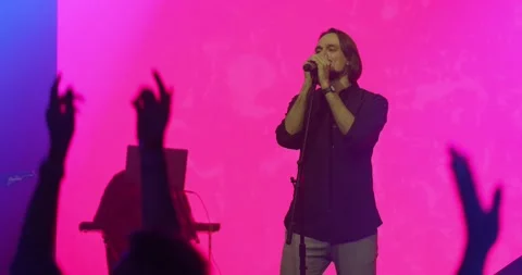 Expressive singer singing into microphone. Live music concert in front of bright Stock Footage 154914142