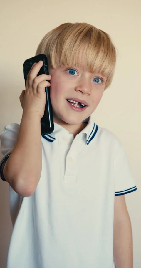 Expressive young boy talking on a smartphone 動画素材 346983314