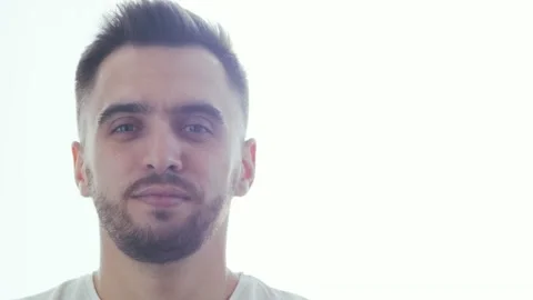 Expressive young man over window background. Home portrait of smiling handsome Stock Footage 130232391