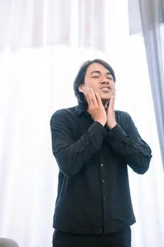 Expressive young man touching his face with a serene and mindful gaze Foto stock