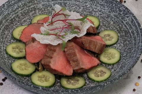 Exquisite medium-rare roast beef salad with cucumber and garnish in bowl, a.. Stock Photos