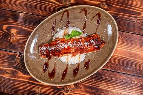 An exquisite presentation of glazed eel sprinkled with sesame seeds and a spr Stock Photos