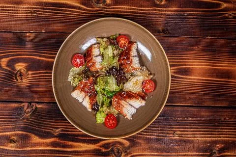 An exquisite presentation of a salad featuring grilled eel, fresh salad leave Stock Photos