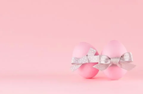 Exquisite soft pink easter eggs with silver bow standing on pastel pink backg Stock Photos