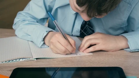 Ext CU, Tracking: Schoolboy does homework, writes a pen in a notebook, on the Stock-Footage 105097195
