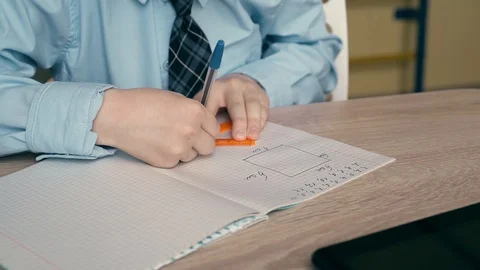 Ext CU, Tracking: Schoolboy does homework, writes pen in a notebook, uses Stock Footage 105097561