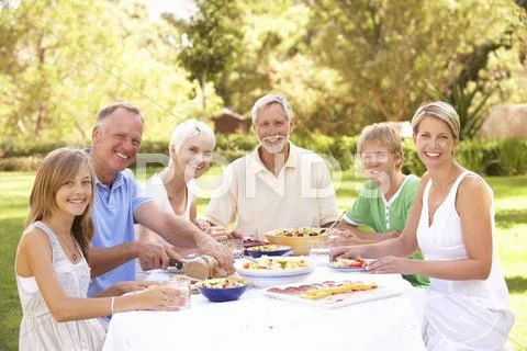 Extended Family Enjoying Meal In Garden Stock Photos