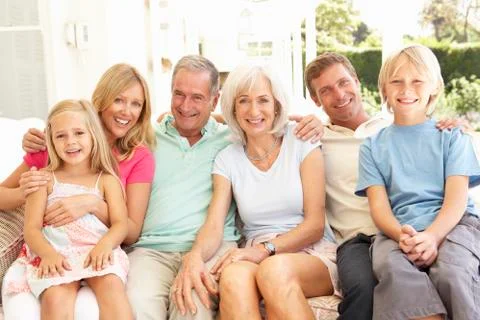 Extended Family Relaxing Together On Sofa Stock Photos