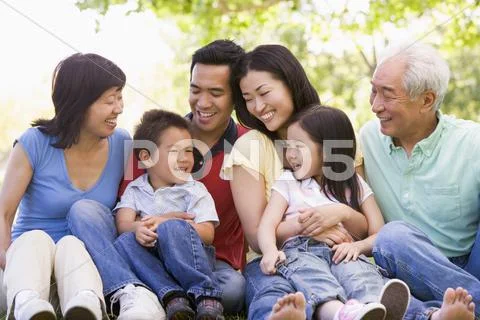 Extended family sitting outdoors smiling Stock Photos