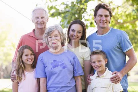 Extended family standing in park smiling Stock Photos