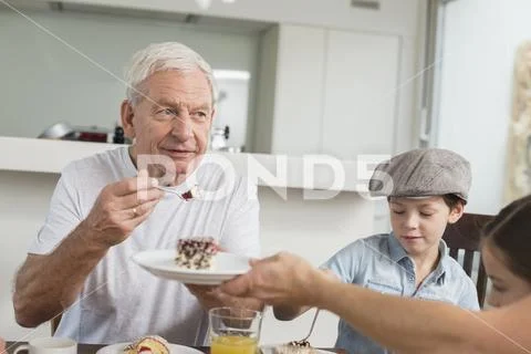 Extended family at table eating cake Stock Photos