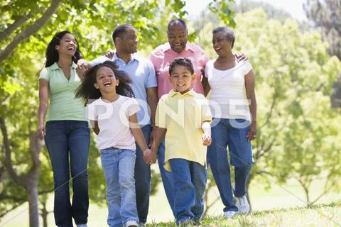 Extended family walking in park holding hands and smiling Stock Photos