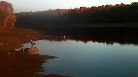 Extended leg pose variations on rock near lake Stock Footage 44119879