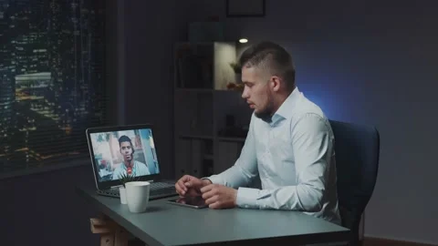 Extended videoconferencing with mixed race boss on computer late at night Stock Footage 157591659