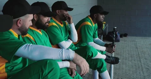 Extending arm second player prompting baseball teammates planning play in dugout Stock Footage 336366690