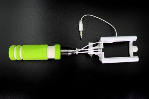 An extensible selfie stick with an adjustable clamp on the end on a white bac Stock Photos