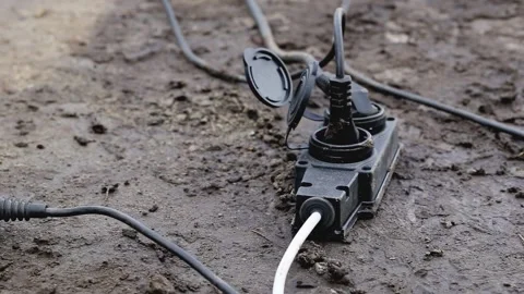 An extension cord with a plug is lying on damp ground. Safety concept during Stock Footage 156950629