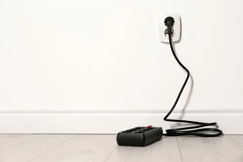 Extension cord with power plug in socket indoors, space for text. Electrician Stock Photos