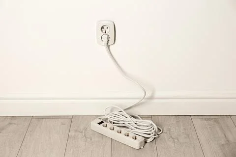 Extension cord with power plug in socket indoors. Electrician's professional  Stock Photos