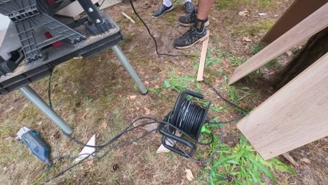 Extension cord reel and tools on outdoor grass workspace for construction Stock Footage 341084080