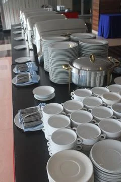Extensive Buffet Setup with Chafing Dishes, Stacked Plates, and Soup Bowls Stockfoto's