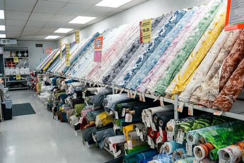 Extensive rolls of fabric are displayed in a well-lit shop environment. Stock Photos