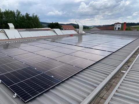 Extensive Solar Panel Array on the Metal Roof of a Large Industrial Facility 库存照片
