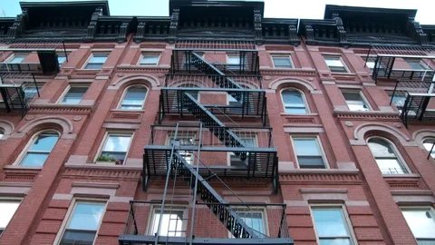 Exterior East Village apartment building with fire escapes, day. Stock Footage