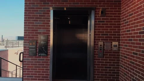 Exterior elevator doors opening and closing on brick building in real time Stock Footage 332630132