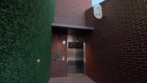 Exterior elevator doors opening in brick corridor with green wall in real time Stock Footage 332630148