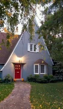 Exterior gray cottage style house with pointed roof and red door at Chico Stock Photos