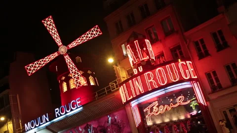 Exterior of the iconic Moulin Rouge night club in Paris illuminated at night Stock Footage