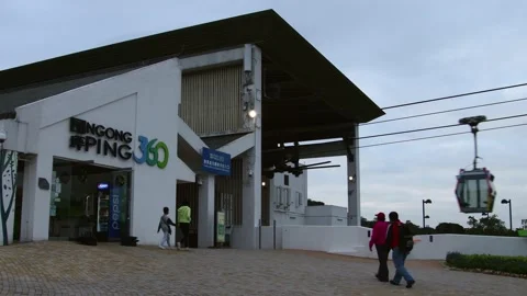 Exterior of Ngong Ping Cable Car Terminal with tourists and cable cars passing Stock Footage 224324852