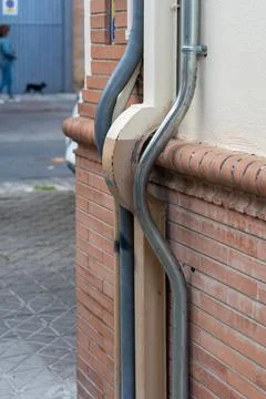 Exterior pipe and rain gutter bending around brick facade Stock-Fotos