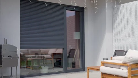 Exterior roller shutter lowering over large window on patio Stock Footage 334050754
