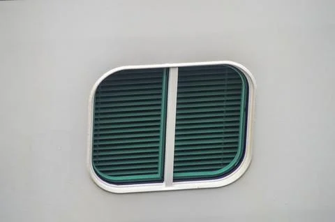 Exterior view of a small, rounded rectangular window with closed green blin.. Fotos Stock