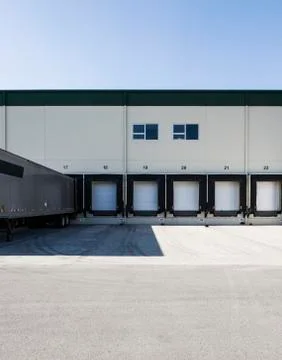 Exterior view of a warehouse loading dock with a truck trailer pulled up to one Stock Photos