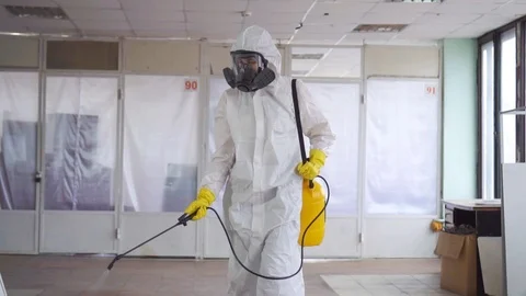 Exterminator in overalls and a protective mask sprays pesticide with a sprayer Stock Footage 105683938