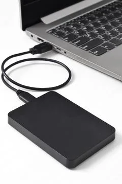 External backup hard disk drive connected to laptop on white background 写真素材