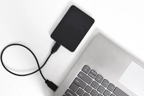 External backup hard disk drive connected to laptop on white background Stock Photos