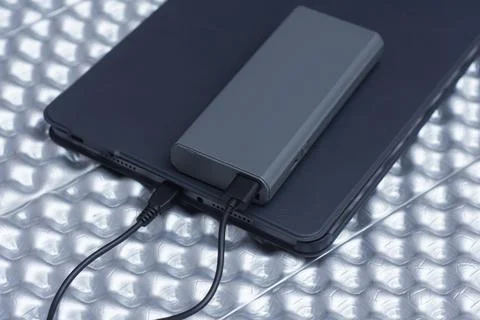 External battery connected by a USB cable to a tablet in a black case. Conc.. Stock Photos